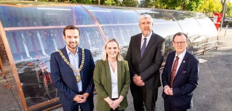 Lord Mayor Councillor Micky Murray, Sara Lynch, Head of Sustainability at Queen’s University Belfast, Infrastructure Minister John O’Dowd and Queen’s President and Vice-Chancellor Sir Ian Greer standing in front of transparent curved bike parking facility